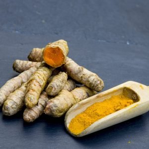 A closeup shot of turmerics with a wooden shovel